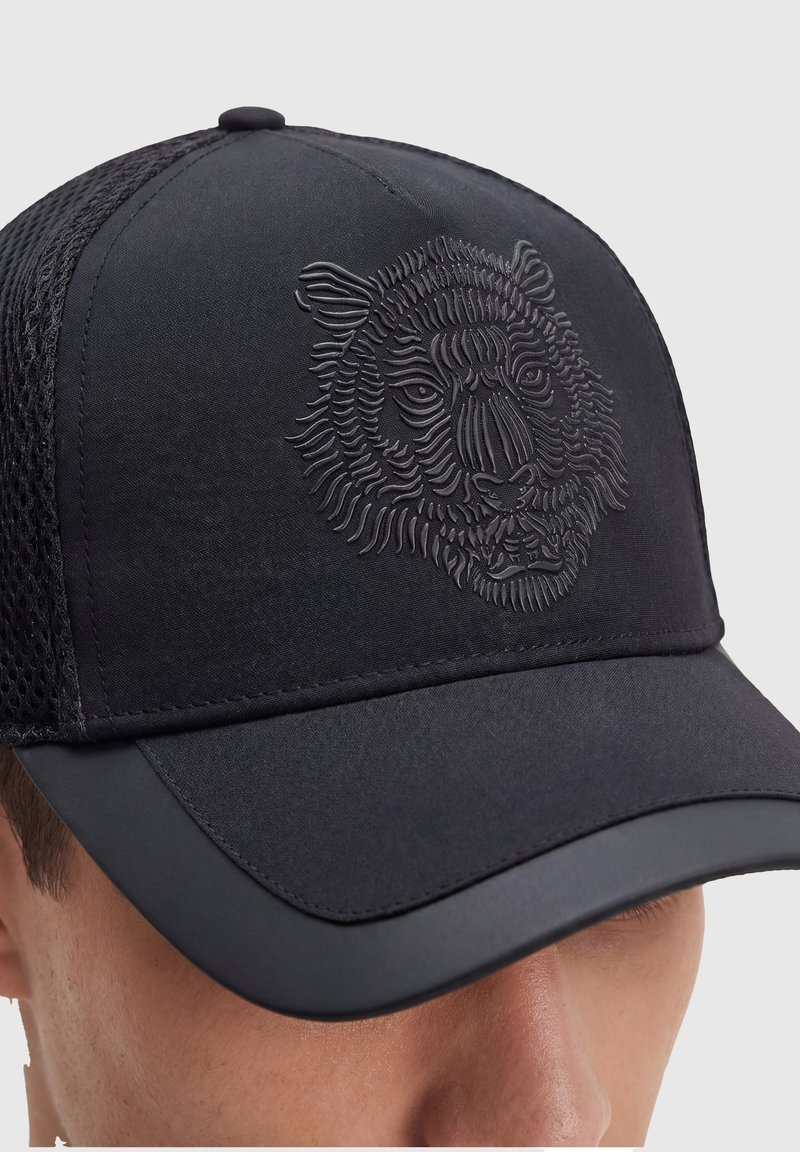 Gorra de béisbol negra con parte trasera de malla y diseño en relieve de cara de tigre, usada por una persona.