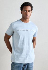 Lichtblauwe katoenen t-shirt met ronde hals en korte mouwen, met het reliëftekst "ANTONY MORATO" over de borst.