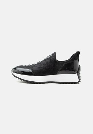 Baskets slip-on noires en tissu texturé, accents brillants au niveau des orteils et du talon, semelle intermédiaire blanche et semelle extérieure noire dentelée, vues de côté.