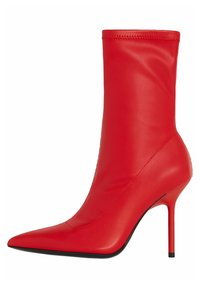 Červená kožená kotníková bota na vysokém podpatku s špičatou špičkou a tenkým stiletto podpatkem, hladký povrch a výška do půli lýtek.