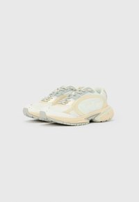 Pari beigejä ja vaaleanharmaita urheilutossuja, joissa on nyörit ja kuvioidut pohjat, valkoisella taustalla.