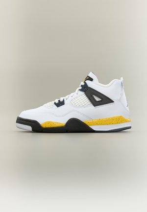Baskets montantes blanches avec des accents noirs et jaunes, panneau latéral en mesh, et détail moucheté jaune sur la semelle intermédiaire sur un fond neutre.