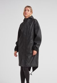 Schwarzer wasserdichter Regenmantel mit Kapuze, langen Ärmeln, elastischen Bündchen und einer vorderen Reißverschlusstasche. Verfügt über einen asymmetrischen Saum und seitliche Eingrifftaschen.