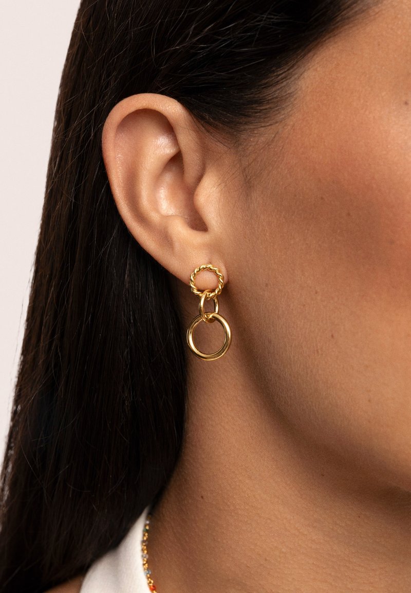 Pendientes en tono dorado que presentan un aro retorcido y un diseño circular doble, destacando un acabado brillante y una estructura en capas.