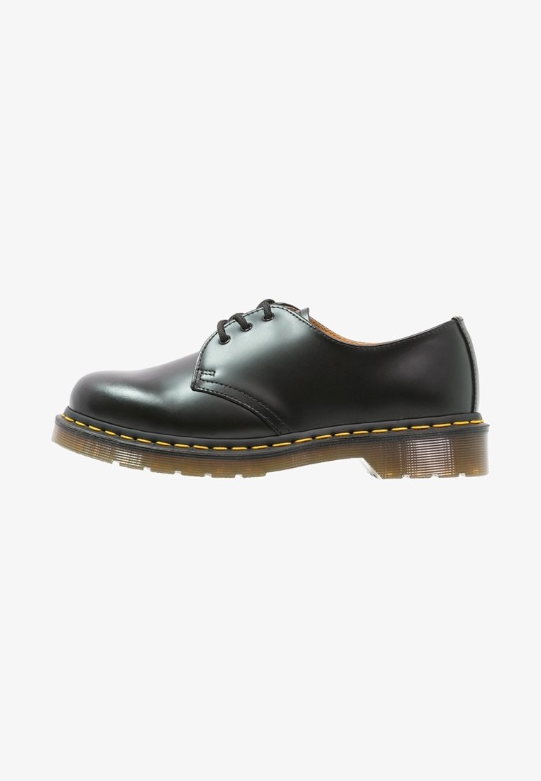 Chaussure Oxford en cuir noir à lacets avec semelle épaisse translucide et surpiqûres jaunes le long du bord de la semelle.
