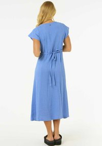 Robe midi de couleur bleu clair en tissu texturé. Elle présente des manches courtes, une taille cintrée par un lien et une silhouette décontractée.