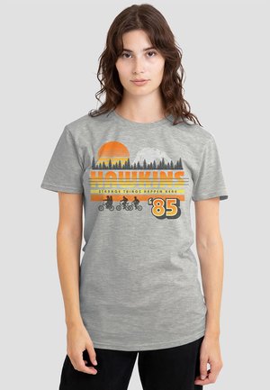 Gray cotton t-shirt with a graphic featuring an orange sun, trees, and bicycles, text reading "HAWKINS STRANGE THINGS HAPPEN HERE '85."