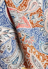 Tela de algodón colorida con un patrón de cachemira en azul, marrón, rosa y blanco, con detalles intrincados y textura suave.