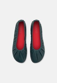 Gröna, plisserade balettisar av mjukt material, med rund tå och kontrasterande röd insida med präglat varumärkesnamn.