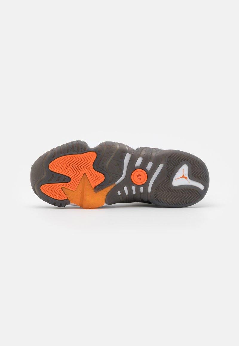 Suola di sneaker in materiale gommoso, con motivi grigi e arancioni, una superficie testurizzata e distintivi elementi di trazione.