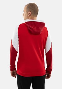 Felpa rossa e bianca con tasca a marsupio, maniche lunghe e cappuccio con coulisse; realizzata in tessuto liscio con dettagli a colori contrastanti.