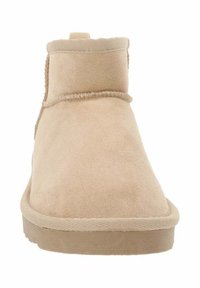 Botín beige hasta el tobillo hecho de ante, con punta redonda, textura suave y un acento de costura a lo largo del borde superior.