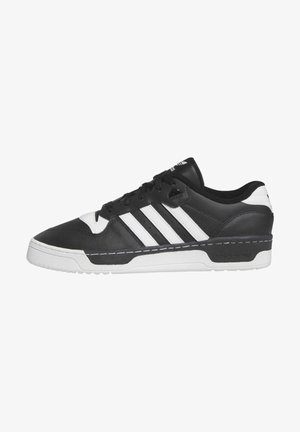 Zwart-witte lage Adidas sneaker met drie witte strepen, zwarte veters en een dikke witte zool op een effen achtergrond.