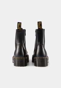 Mustad mustad mustad läikiva viimistlusega mustad nahast ankle boots, kollane õmblus, silmapaistev tagumine tõmblukk, robustne must tall ja külgmine tõmblukk.