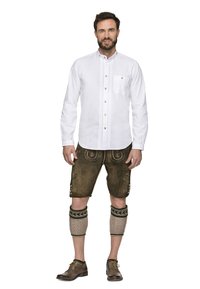 Weißes Langarmhemd mit Knöpfen und Tasche, kombiniert mit braunen Lederhosen, die mit Stickereien verziert sind, und knielangen Stricksocken.