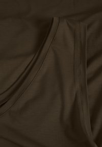 Pruun tank top, mis on valmistatud pehmest, venivast kangast. Omab siledat tekstuuri, laia kaelust ja kõverat äärestust.