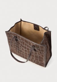 Sac fourre-tout en cuir gaufré crocodile marron avec des coutures claires, d'ouverture sur le haut et deux poignées robustes. Intérieur en tissu beige.