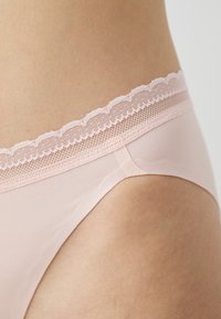 Chiloți roz cu dantelă, având o textură netedă și un elastic în talie, decorat cu detalii unduite pe marginea superioară.