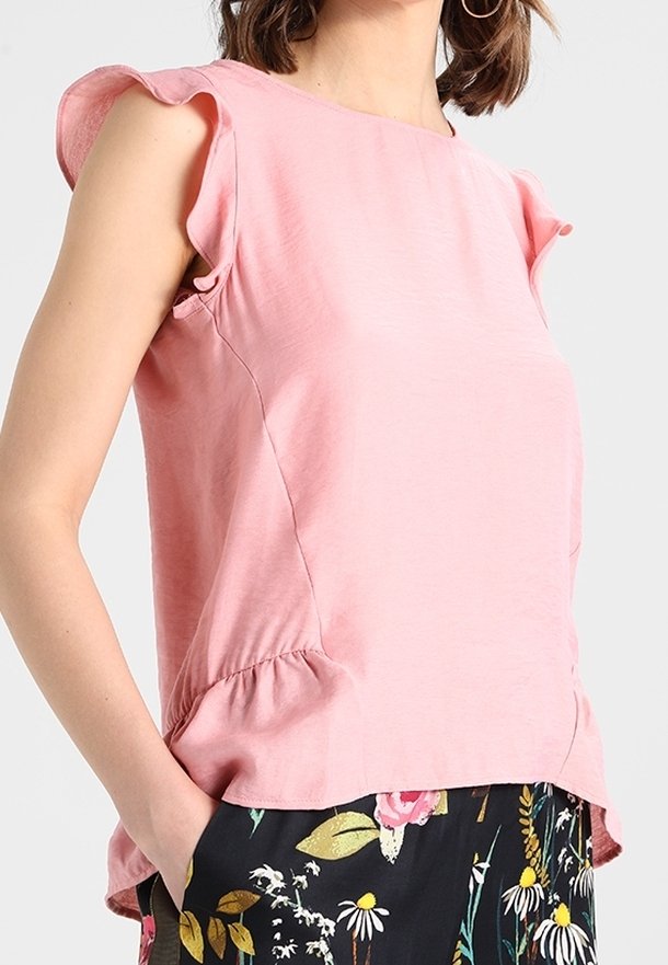 Růžový top s krátkým rukávem, s volánkovým detailem na ramenou, kulatým výstřihem a peplum spodním lemem, v kombinaci s květinovým vzorem na kalhotách.