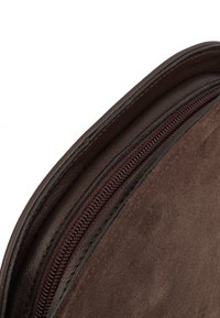 Angolo di una borsa in suede marrone con una cerniera, dotata di rifiniture in pelle scura. La texture è liscia e la cerniera è completamente funzionante.