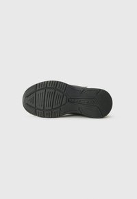 Semelle de sneaker noire en caoutchouc texturé, avec un motif de semelle pour l'adhérence, nom de marque embossé et un design de bout arrondi.