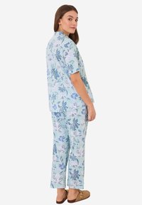 Blommigt loungewear-set i ljusblått och grönt, med korta ärmar, vida byxor och mjukt tyg med en lätt texturerad yta.