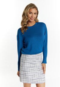 Maglione blu lavorato a maglia con maniche lunghe abbinato a una gonna mini a quadri bianca e blu con una texture. Collo rotondo semplice, vestibilità comoda.