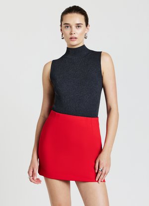 Haut sans manches noir à côtes avec col montant, associé à une mini-jupe rouge ajustée, présentant une texture lisse et des lignes épurées.