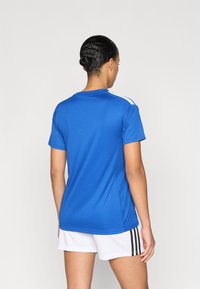 Μπλε αθλητική μπλούζα από ελαφρύ ύφασμα, με κοντά μανίκια και λευκές ρίγες στους ώμους, με στρογγυλή λαιμόκοψη.