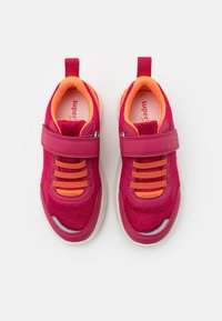 Ein Paar lebhaft pinkfarbene und orangefarbene Sneakers für Kinder mit Klettverschlüssen und reflektierenden Details, von oben auf einem weißen Hintergrund betrachtet.