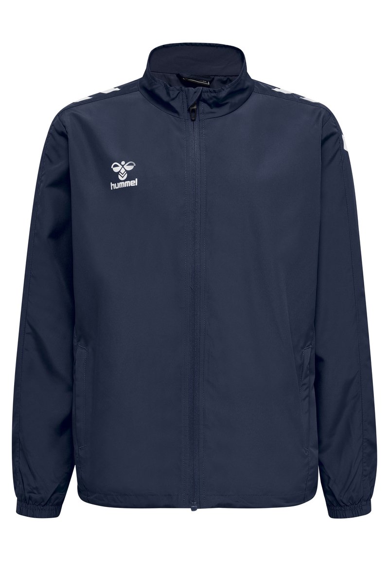 Marinblå lättviktsjacka med fullständig dragkedja fram, stående krage och elastiska ärmslut. Har vit logotyp och axelaccenter.