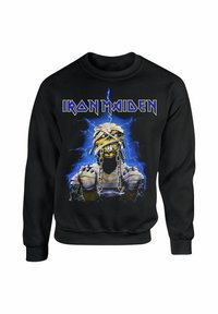 Černá mikina s logem "Iron Maiden" v žluté barvě. Centrální grafika zobrazuje postavu připomínající mumii s řetězy na modrém elektrickém pozadí.
