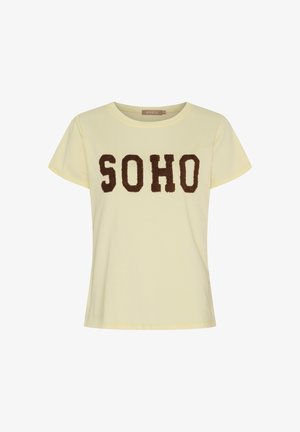 Lysegul t-shirt med korte ærmer og rund halsudskæring, dekoreret med store brune teksturerede bogstaver, der staver "SOHO" hen over brystet.