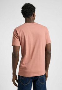 Koszulka z krótkim rękawem, okrągłym dekoltem w jasnoróżowym kolorze, wykonana z bawełny, charakteryzująca się gładką teksturą i luźnym krojem. Brak widocznych wzorów lub akcentów.