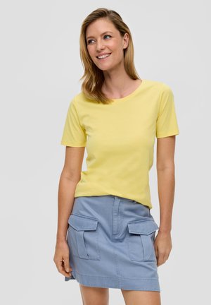 T-shirt jaune à manches courtes associé à une jupe cargo bleu clair avec deux poches avant et une coupe droite. Texture en coton lisse.