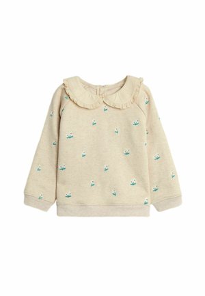 Beżowy sweter dla malucha z długim rękawem, z falbankowym kołnierzykiem typu Peter Pan oraz drobnymi białymi kwiatkami z zielonymi liśćmi rozsianymi po tkaninie.