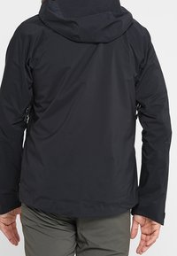 Sort udendørsjakke med hætte, der har en glat tekstur og justerbare manchetter. Indeholder sidelommer og elegante design elementer.