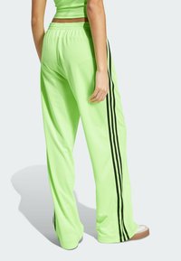 Neon groene sweatpants met een ontspannen pasvorm, met drie verticale zwarte strepen langs de buitennaad en een elastische tailleband.
