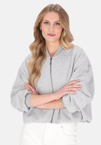 Szara kurtka typu bomber na zamek, wykonana z miękkiej tkaniny bawełnianej, o luźnym kroju, z prążkowanymi mankietami i okrągłym kołnierzem.