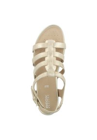 Sandalo beige con cinturini, caratterizzato da una finitura metallica, design con punta aperta, soletta imbottita e cinturino alla caviglia regolabile con hardware in tonalità oro.