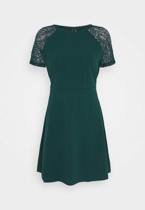 Vihreä mekko, jossa on lyhyet pitsihihat, pyöreä kaula-aukko, vartalonmyötäinen yläosa ja levenevä hame. Valmistettu pehmeästä, joustavasta materiaalista.