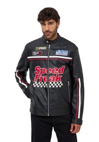 Giubbotto in pelle nera con pannelli imbottiti sulle spalle, dotato di strisce rosse e bianche, testo "Speed Freak" e loghi da corsa. Chiusura con zip argento.
