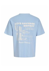 Helehall sinine T-särk valge väljakujutusega väliskohvikust, tekst "Côte Sauvage Bistrot," prantsuse keelne fraas ja "French Riviera" tagaküljel.