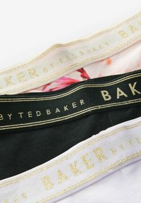 Tre par elastiske underbukser i beige, sort og lavendel med guldtryk "BY TED BAKER" og blomstermønster på den beige kant.