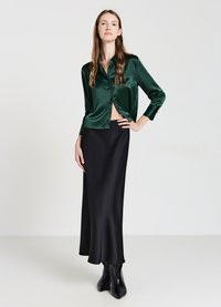 Green satin button-up blouse paired with a black satin maxi skirt. The blouse has a cropped silhouette and long sleeves, and the skirt flows to the floor.