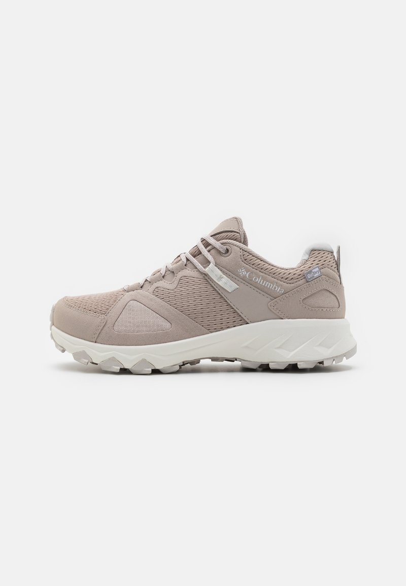 Lys beige idrettssko med mesh og semsket skinn, en polstret hvit såle og et sikkert snøresystem. Teksturierte detaljer på sidene.