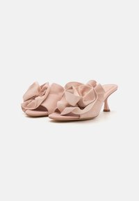 Muli din suede roz, cu accente fronsate în față, design cu vârful deschis și un toc subțire, alungit. Textură moale și siluetă feminină.