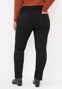 Svarta jeans i denim med hög midja, slim fit, två bakfickor och en slät yta. Matchas med svarta klackstövlar.