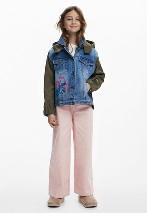 Jeansjacka med gröna ärmar, framfickor och Stitch-grafik. Matcher med ljusrosa vida byxor och beiga skor.