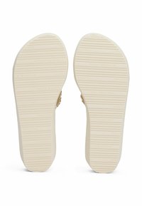 Suela blanca de una zapatilla con surcos texturizados y logo en relieve; superficie lisa con una ligera curva en los bordes, diseñada para el agarre.